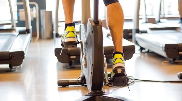 Athletic-man-cycling-on-stationary-bike-in-gym-
